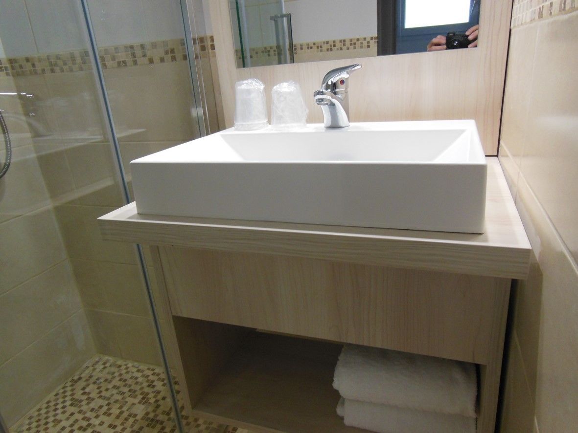 A bathroom with a white sink, a mirror, and a shower.