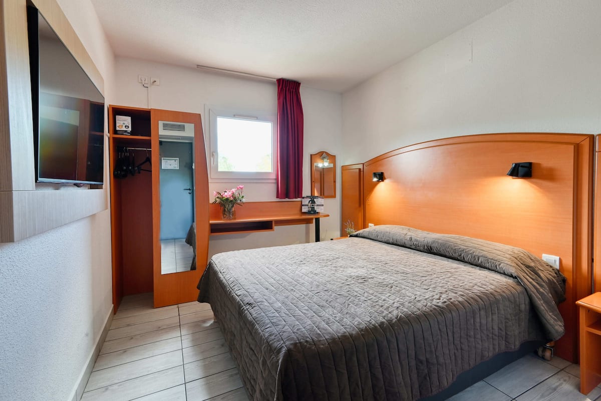 Une chambre à coucher avec un lit, un bureau, un miroir et une armoire.