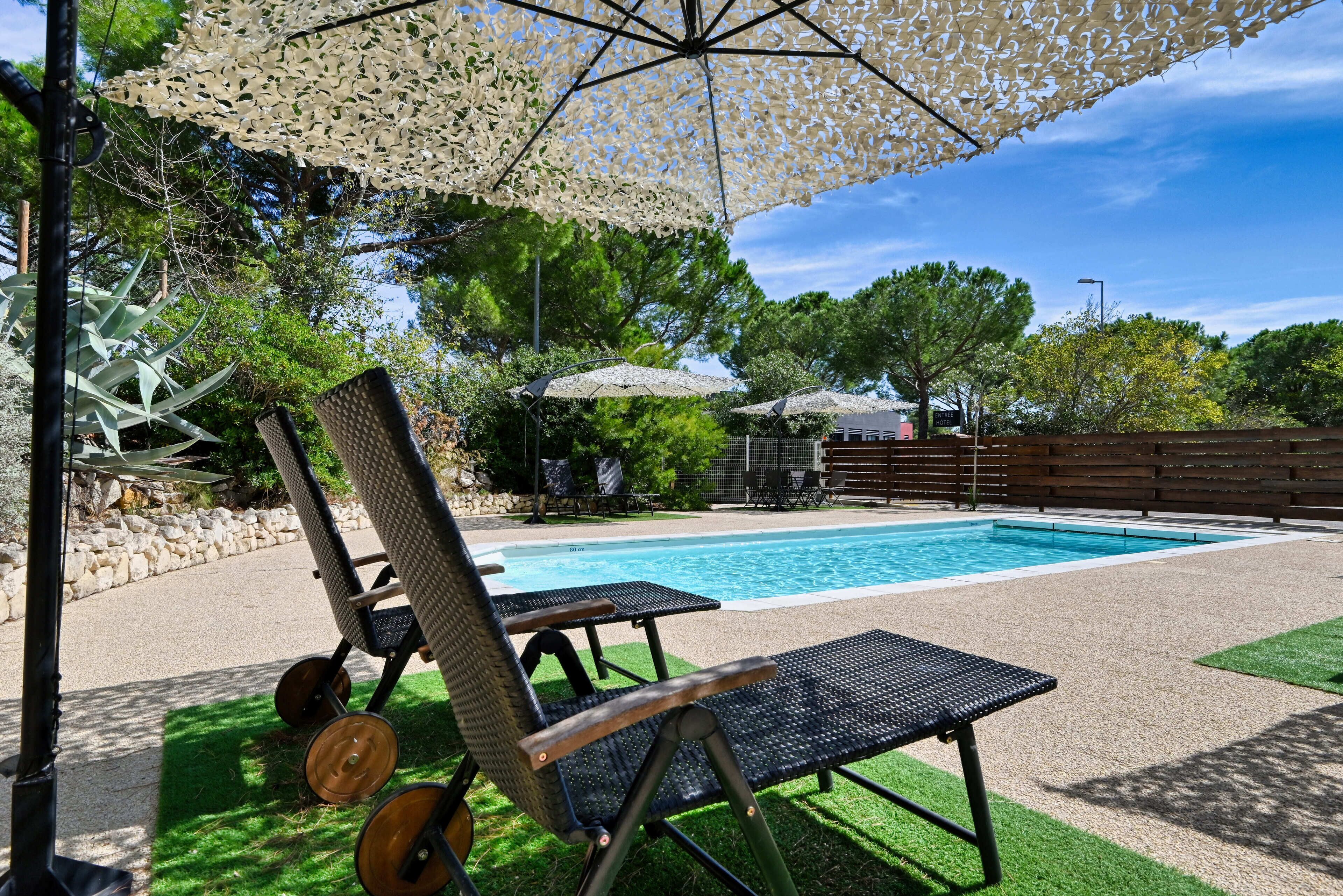 Zona junto a la piscina con piscina, sillas de descanso y sombrillas.
