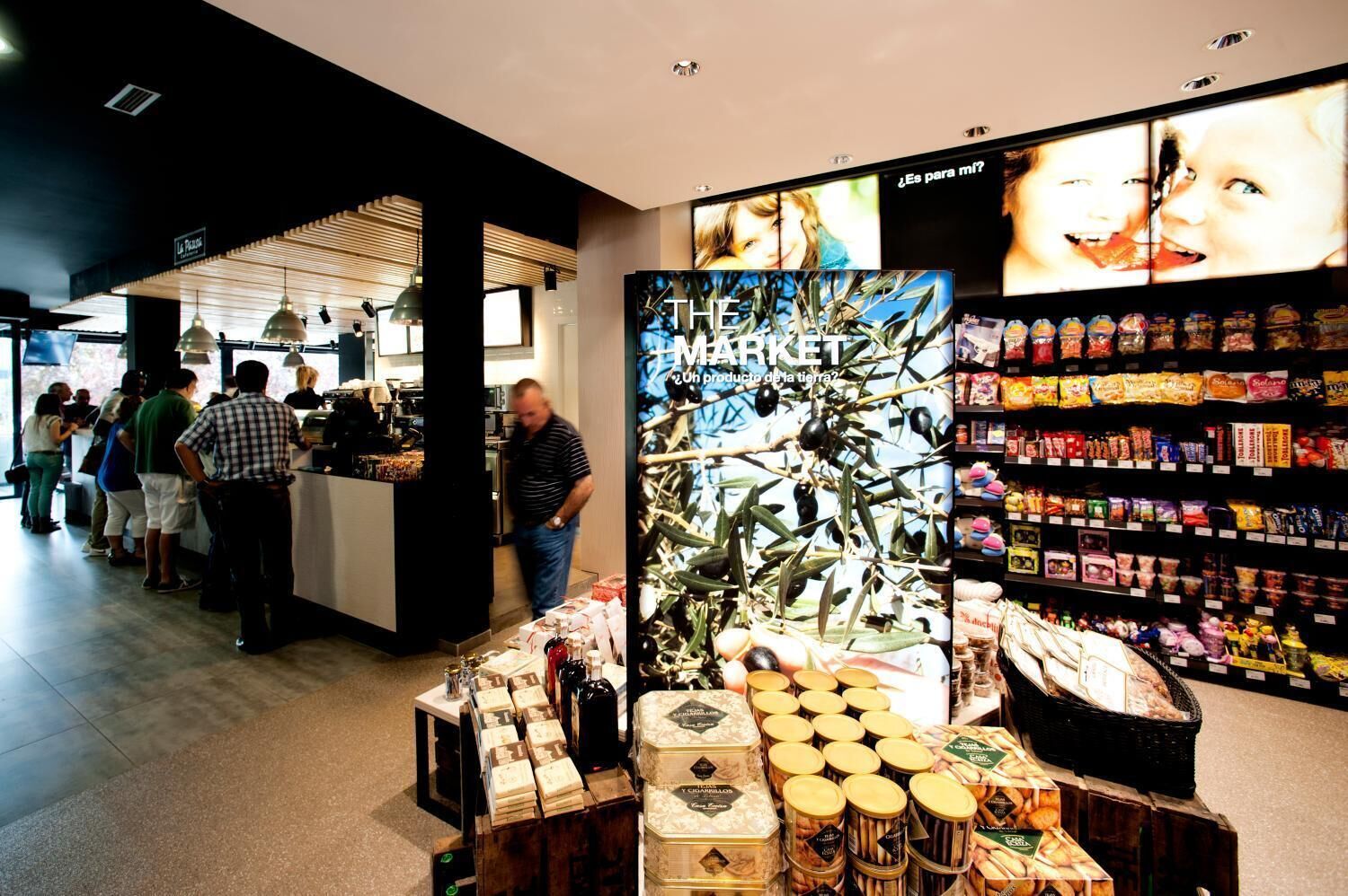 A modern retail store with a variety of packaged goods on shelves and a display of olive oil bottles.
