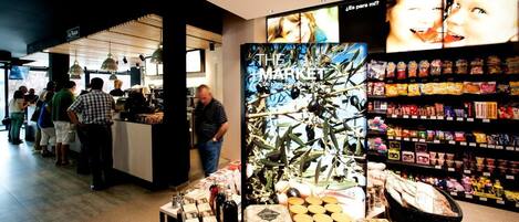 A modern retail store with a variety of packaged goods on shelves and a display of olive oil bottles.