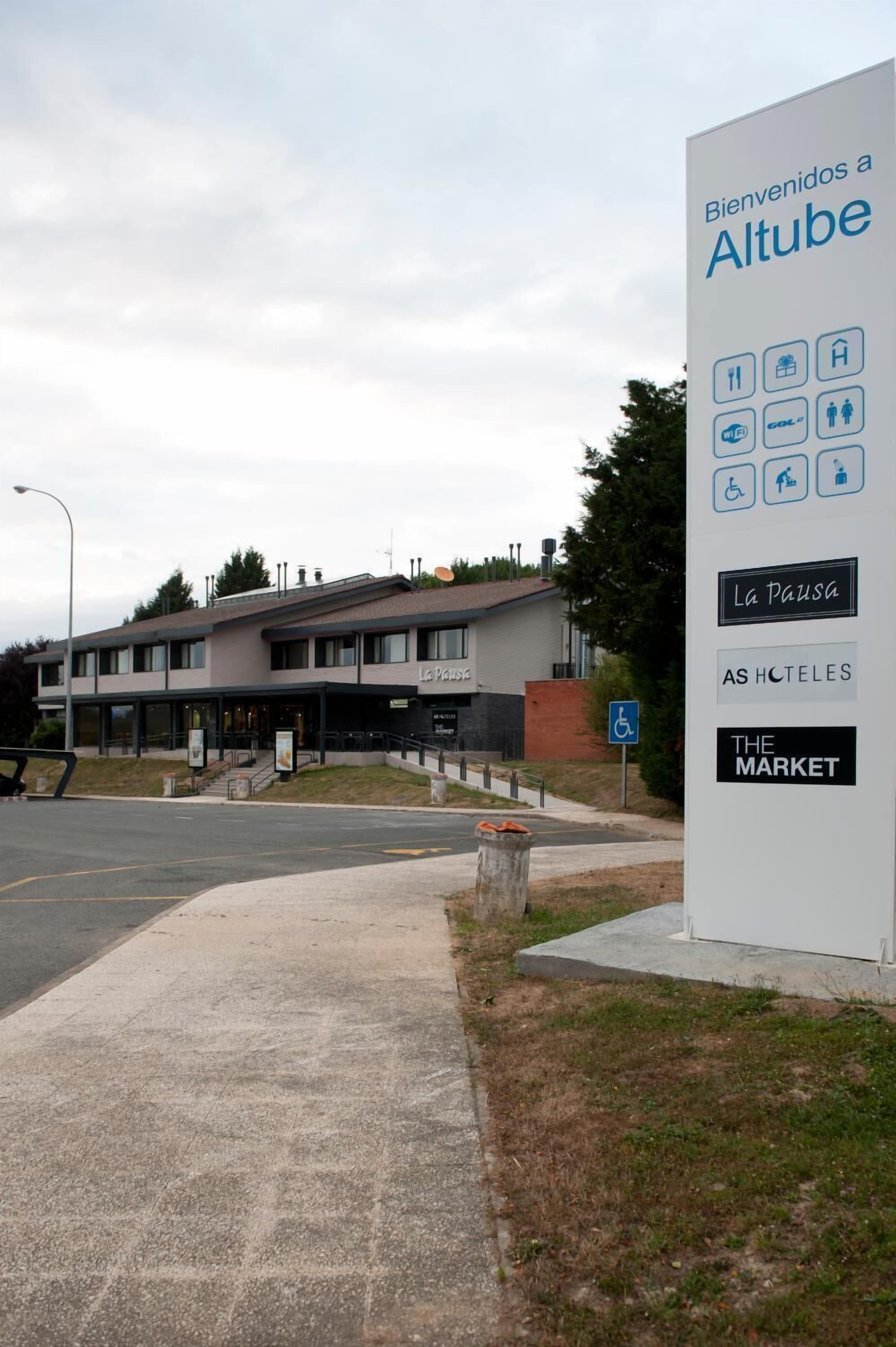 L’entrée d’un hôtel, avec un panneau indiquant les services proposés, tels qu’un restaurant, un parking et un marché.