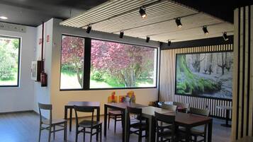 Comedor con techo alto, ventanas amplias con luz natural y vista a árboles.