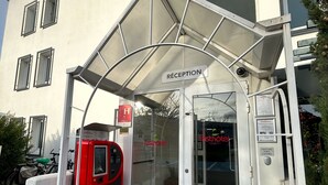 L’entrée d’un hôtel, avec un espace d’accueil, un terminal de paiement numérique et un panneau indiquant la réception.