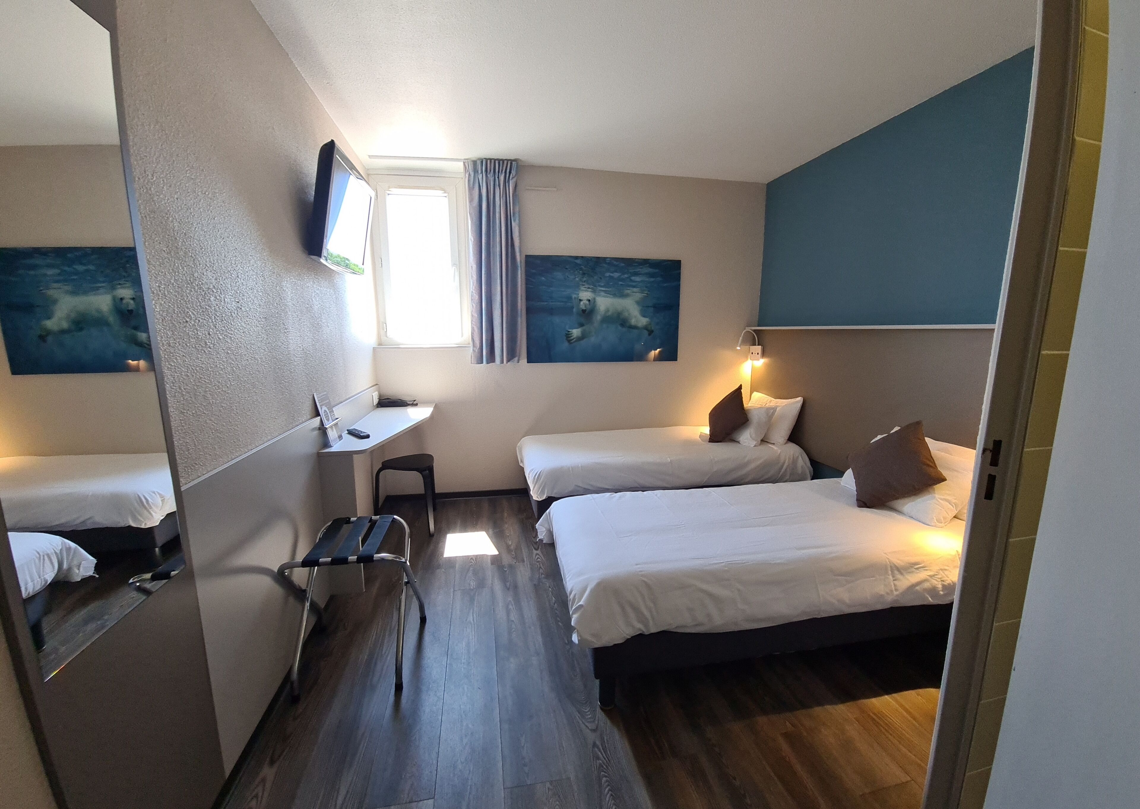 Una habitación de hotel con dos camas, un escritorio, una silla y un televisor.