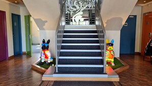 Een trap met een sierhekwerk en twee dierenbeeldjes aan de voet.