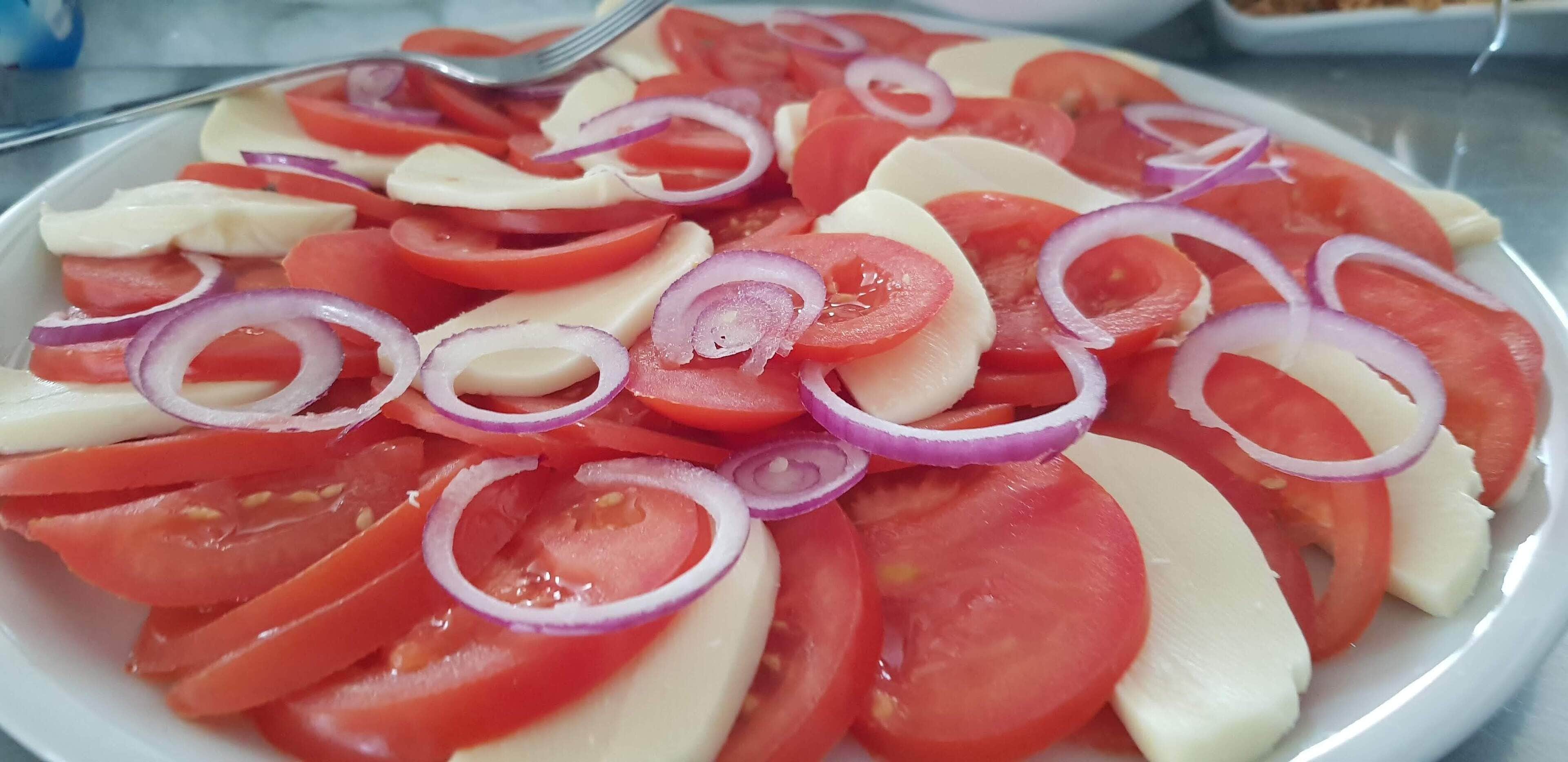 Un plato de rodajas de tomate, cebolla y queso.