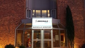 Een hotel met een bord waarop te lezen is: 'The Originals Hotel Restaurant' en 'Marseille Airport', wat de locatie aangeeft.