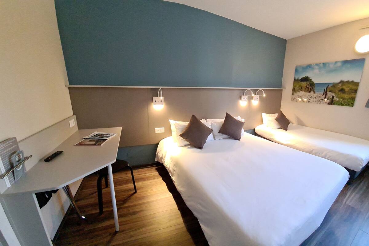 Una habitació d'hotel amb dos llits, un escriptori i una taula petita.
