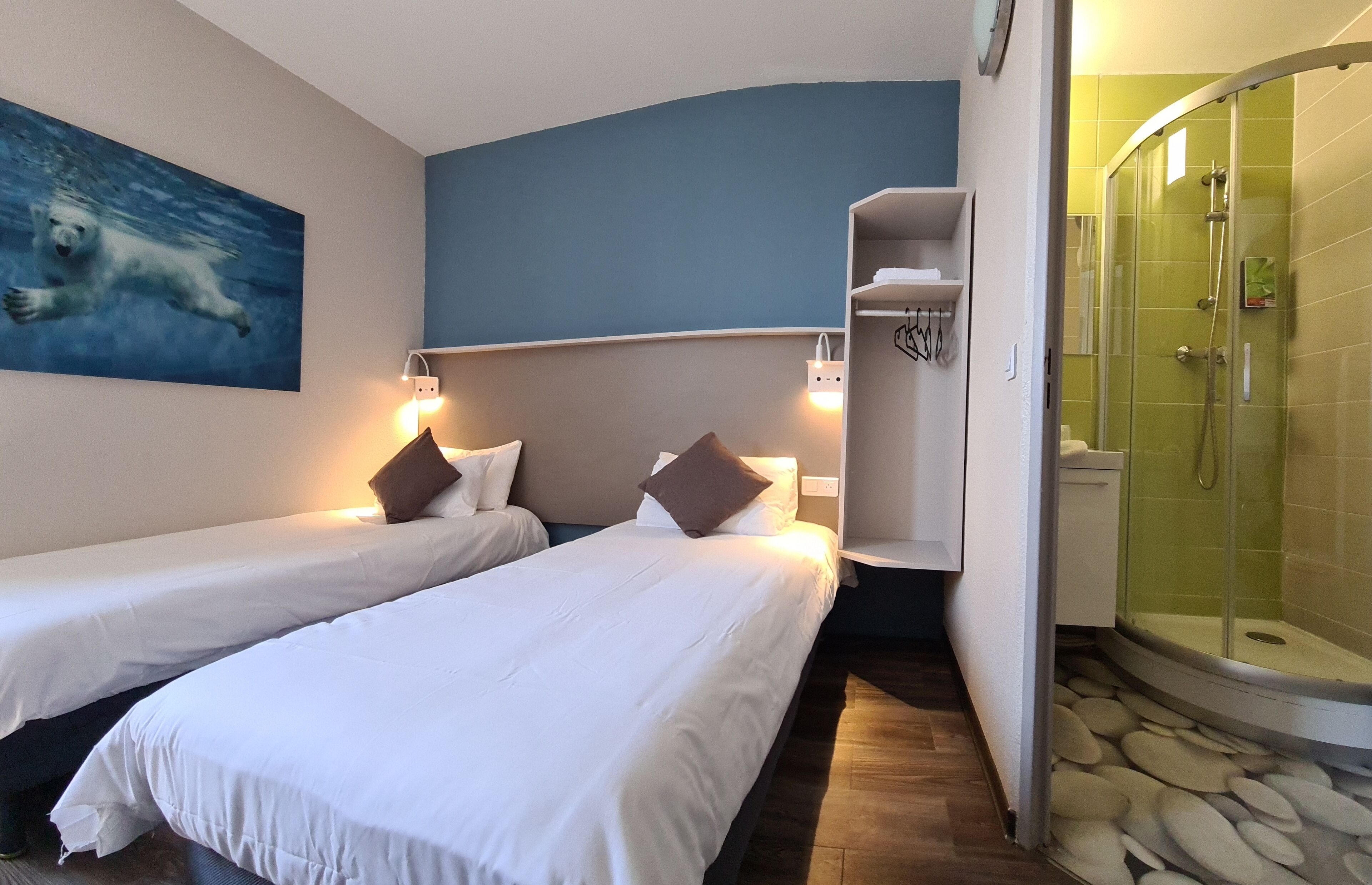 Une chambre d’hôtel avec deux lits, une douche et un tableau représentant un ours polaire.