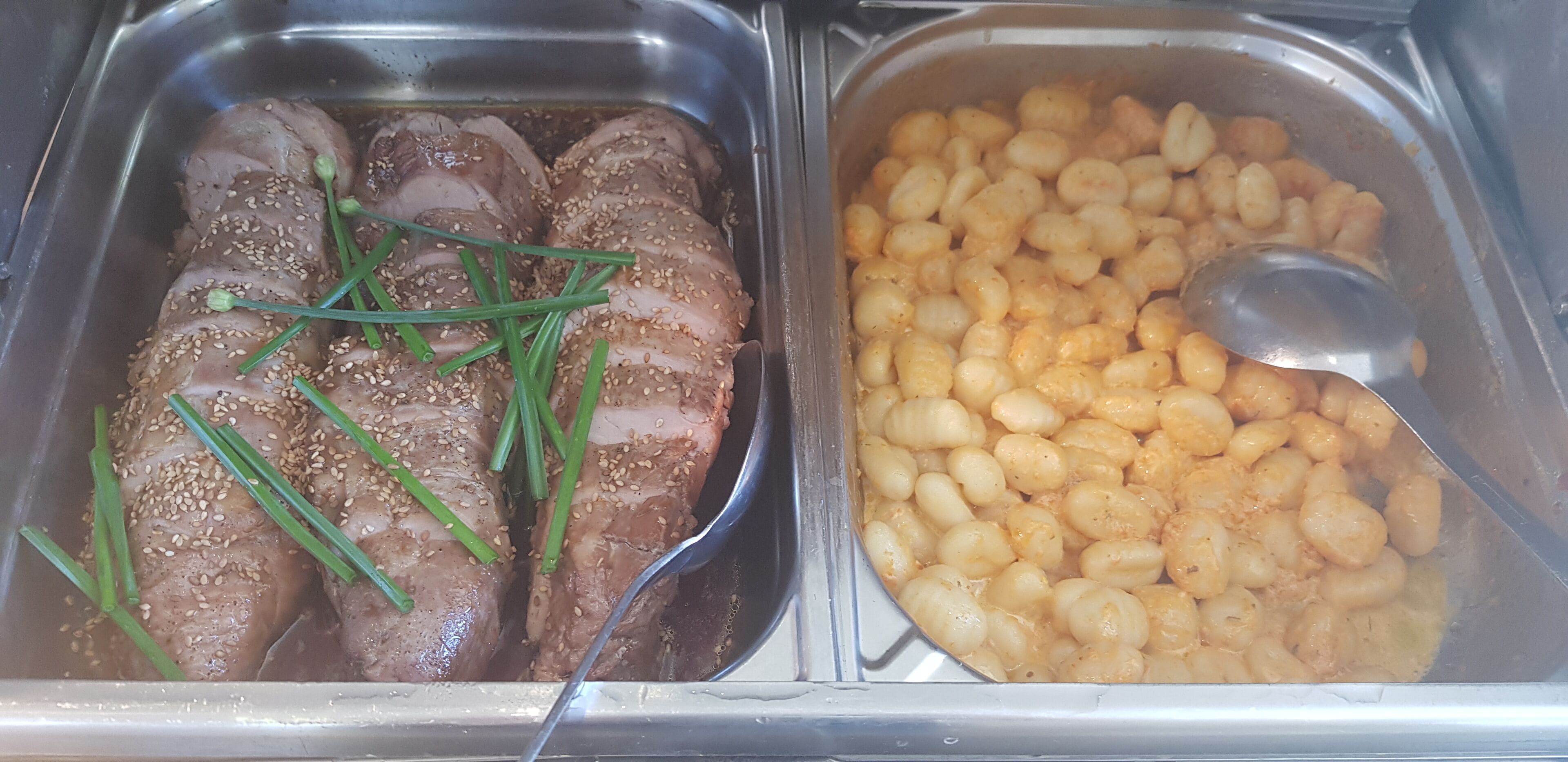 Un bufé con carnes en rodajas y diversas opciones de pasta.