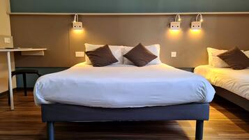 Habitación de hotel con una cama grande, dos mesitas de noche, un escritorio y lámparas de lectura fijadas a la pared.