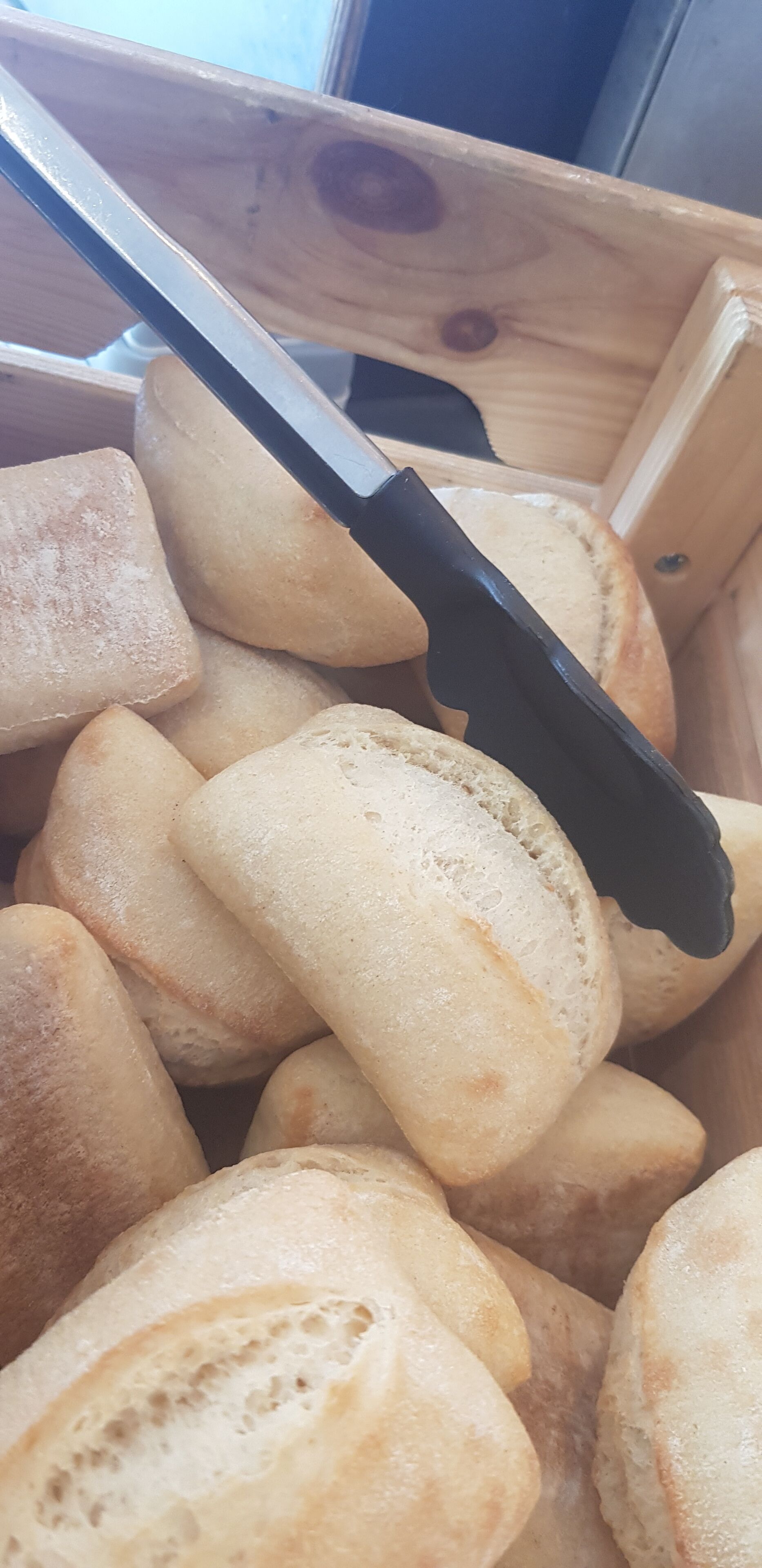 Una caja de madera llena de panecillos redondos y dorados.