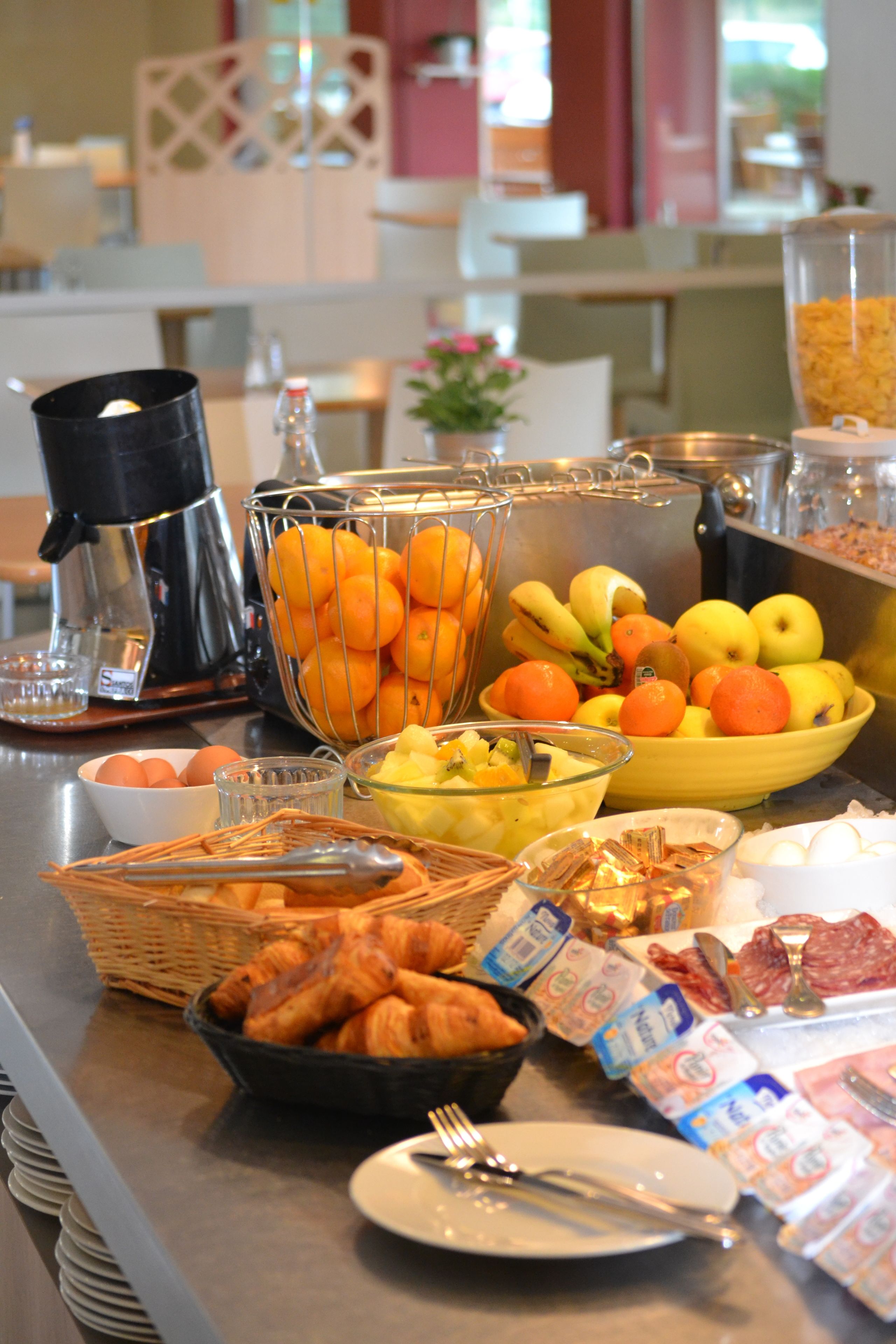 A buffet with various food items including fruits, pastries, and beverages.