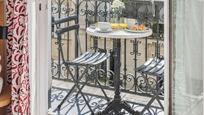 A balcony with a table set for breakfast, a chair, and a view of a building with a balcony. - Alexandrine Opera (Paris)