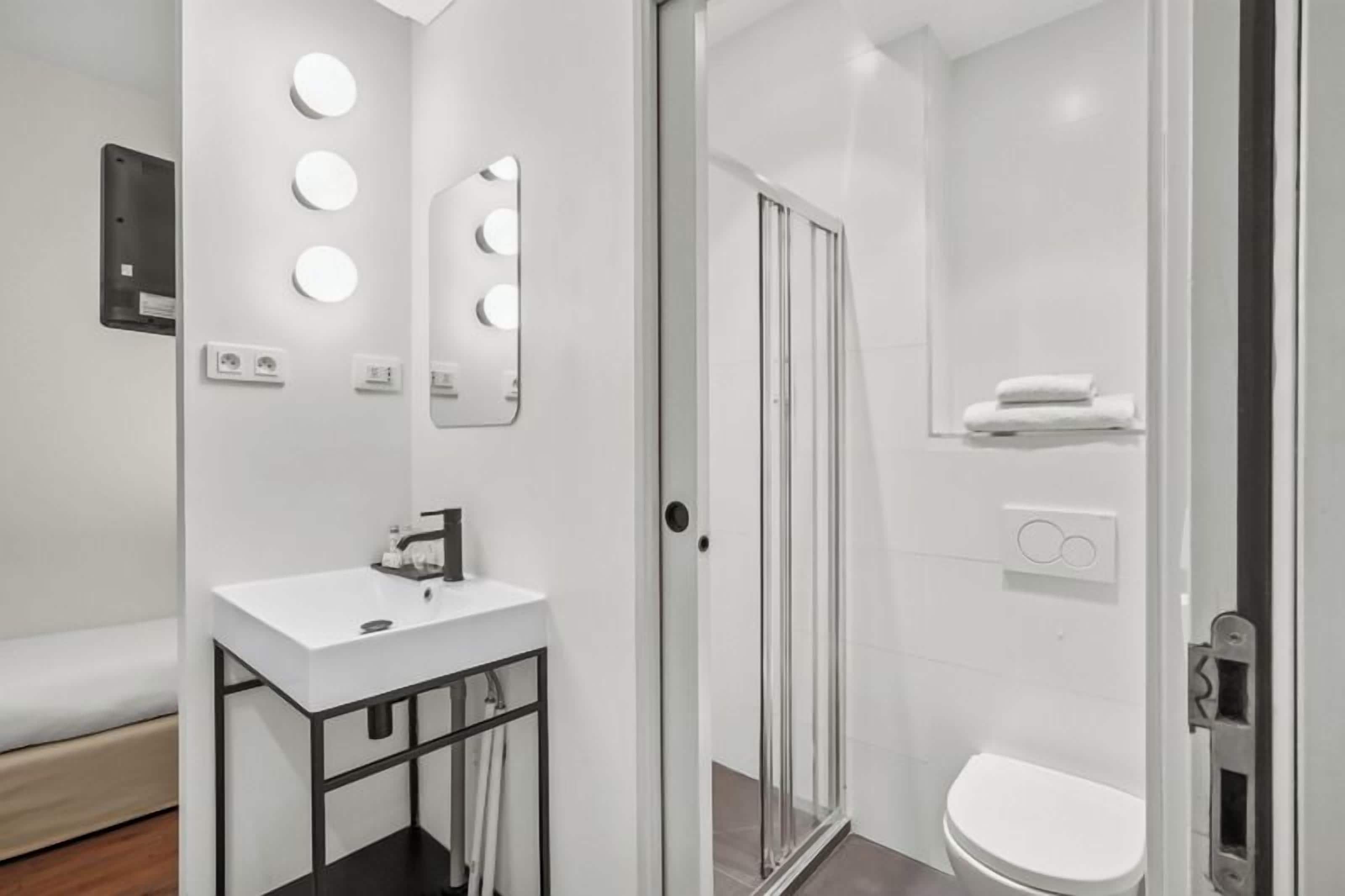 A modern bathroom with a white sink, mirror, and shower.