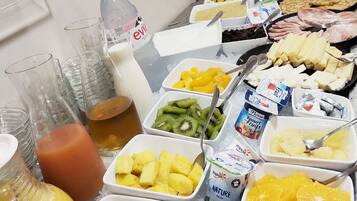 Un bufé con una variedad de alimentos, entre ellos frutas, yogur y bocadillos empaquetados.