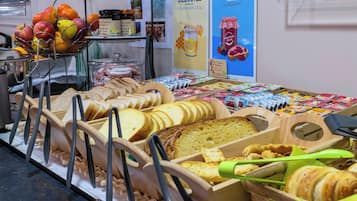 Een bakkerijdisplay met verschillende broden, gebak en jam.