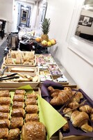 A buffet with various food items including bread, pastries, and fruits.