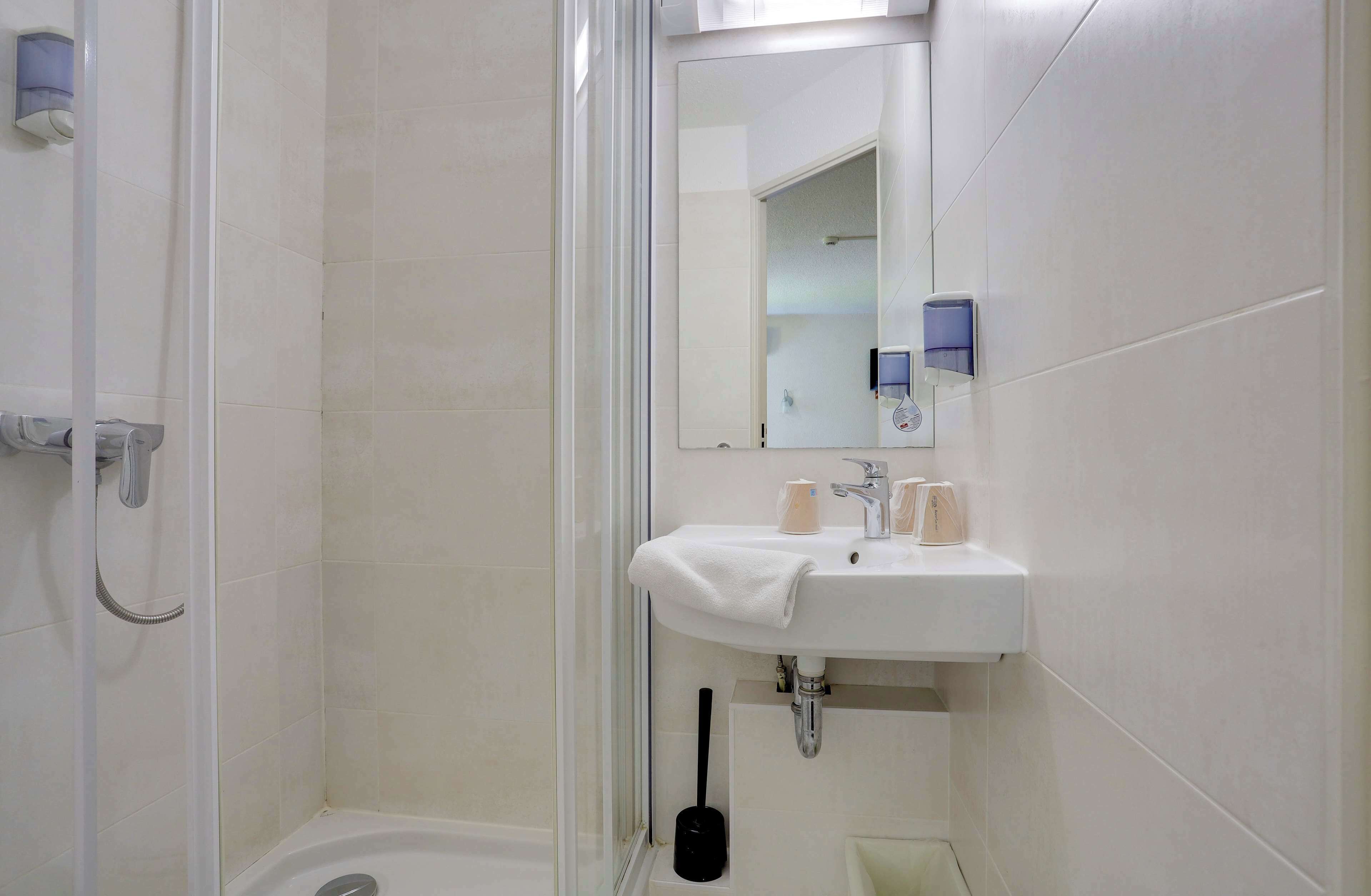 A bathroom with a white sink, mirror, and shower.
