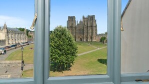 A view of a historic cathedral through a window, with a clear sky and a tree in the foreground. - The Ancient Gatehouse Hotel (Wells)