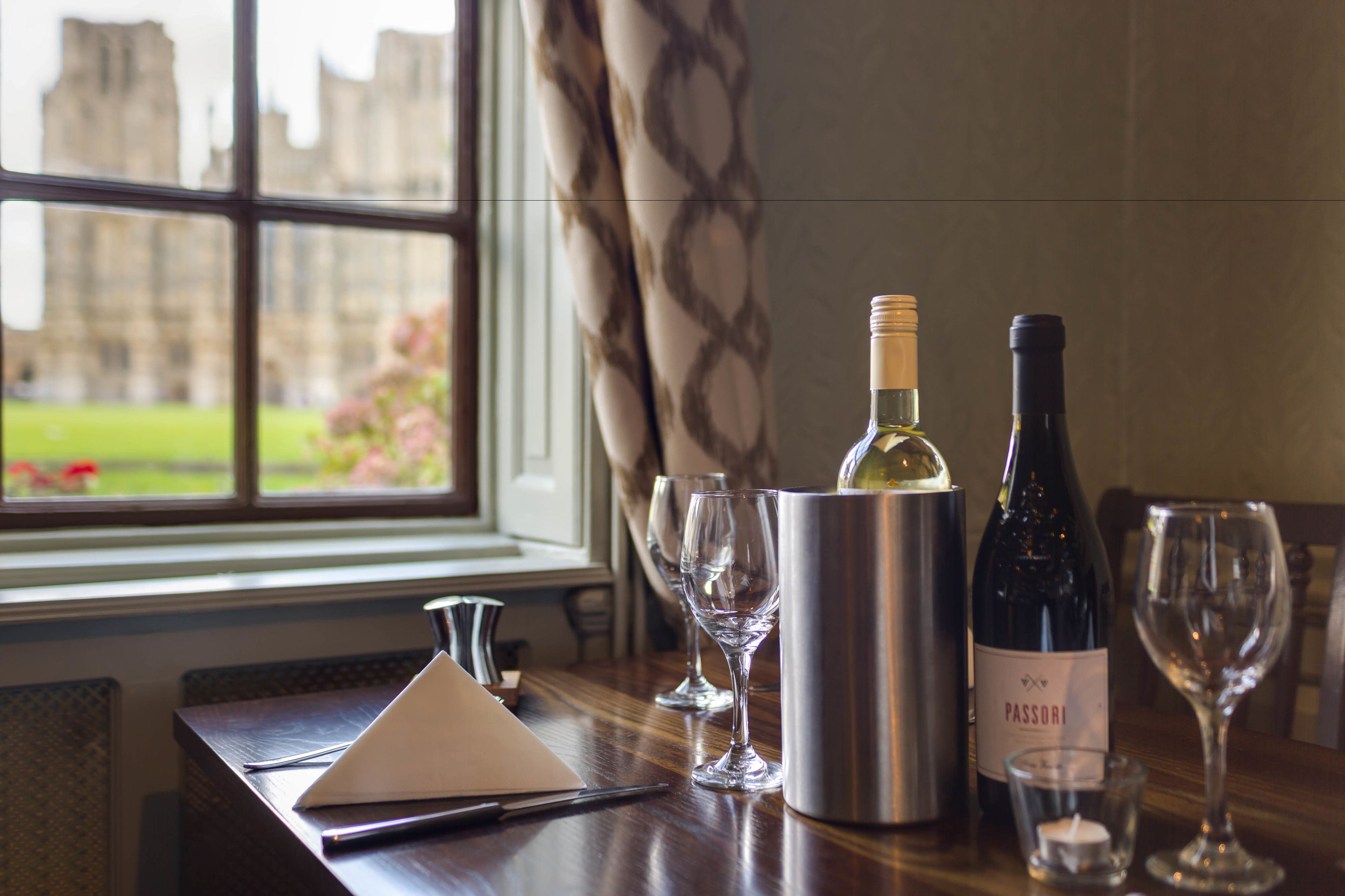 A table with a wine bottle, glasses, and a notebook.