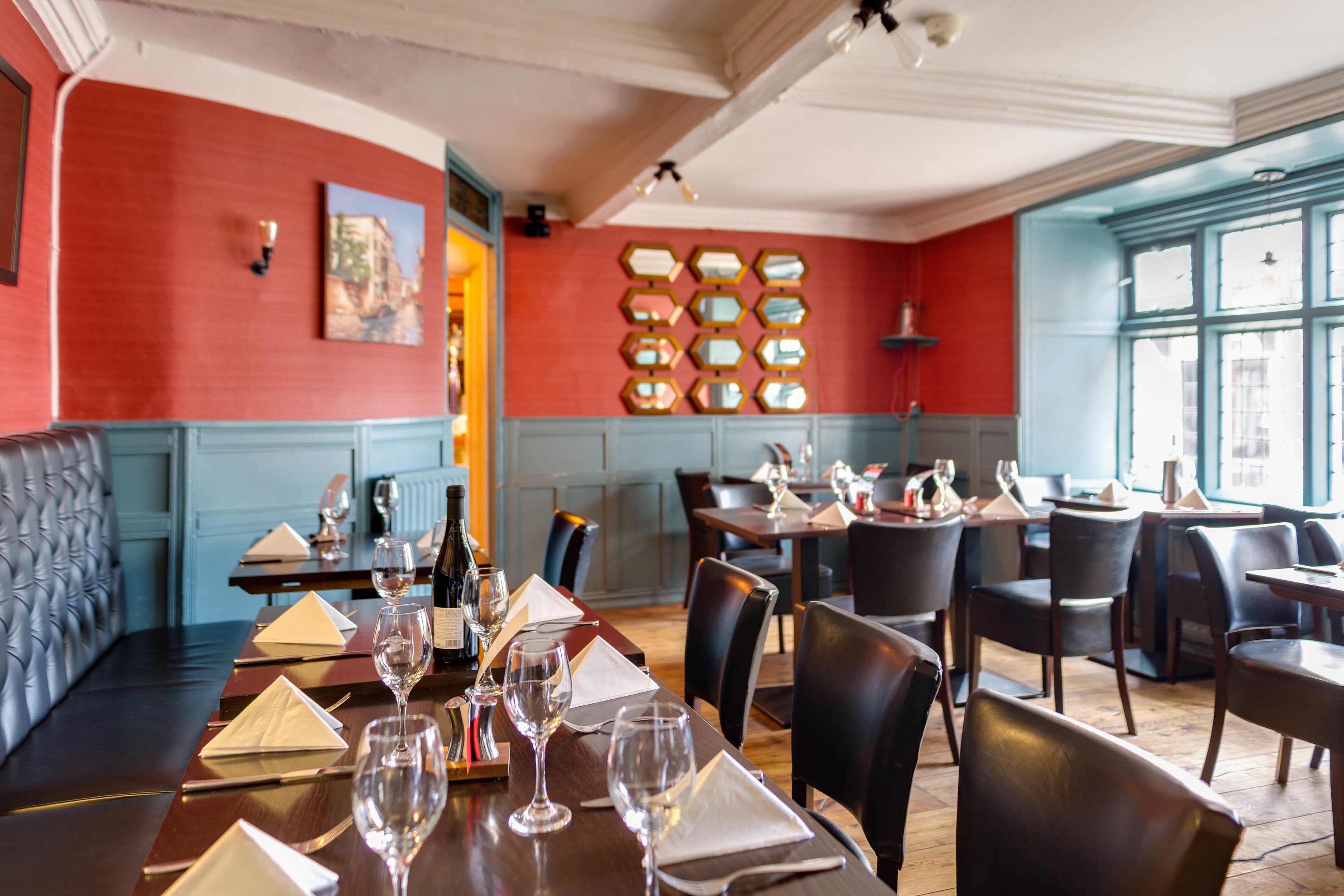 A restaurant with a red and blue color scheme, wooden tables, and black leather chairs.