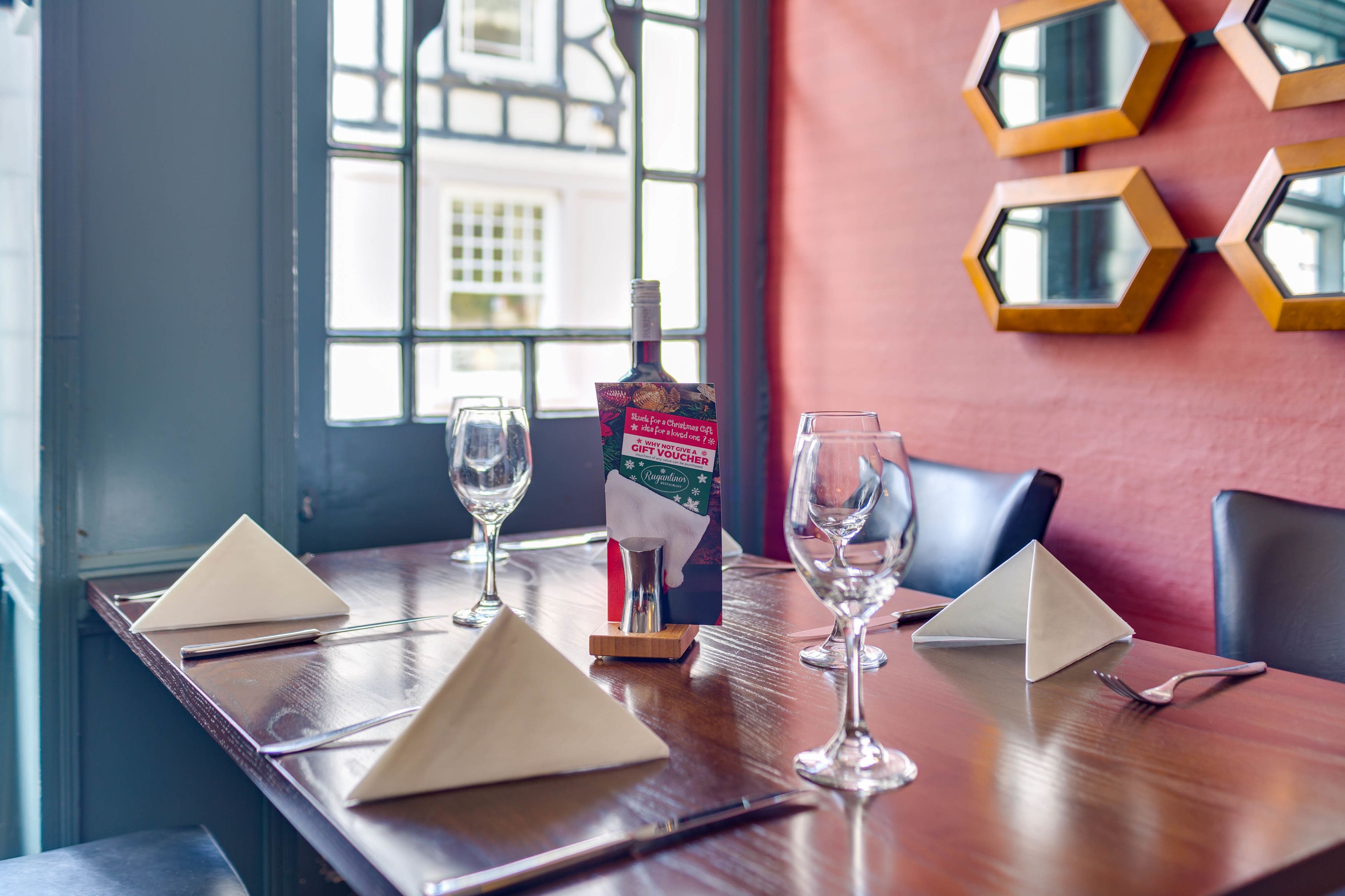 A dining table set with wine glasses, a bottle, and a gift voucher.
