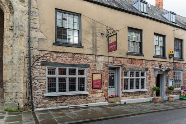 A traditional stone building with multiple windows and a sign for 'Regent's'. - The Ancient Gatehouse Hotel (Wells)