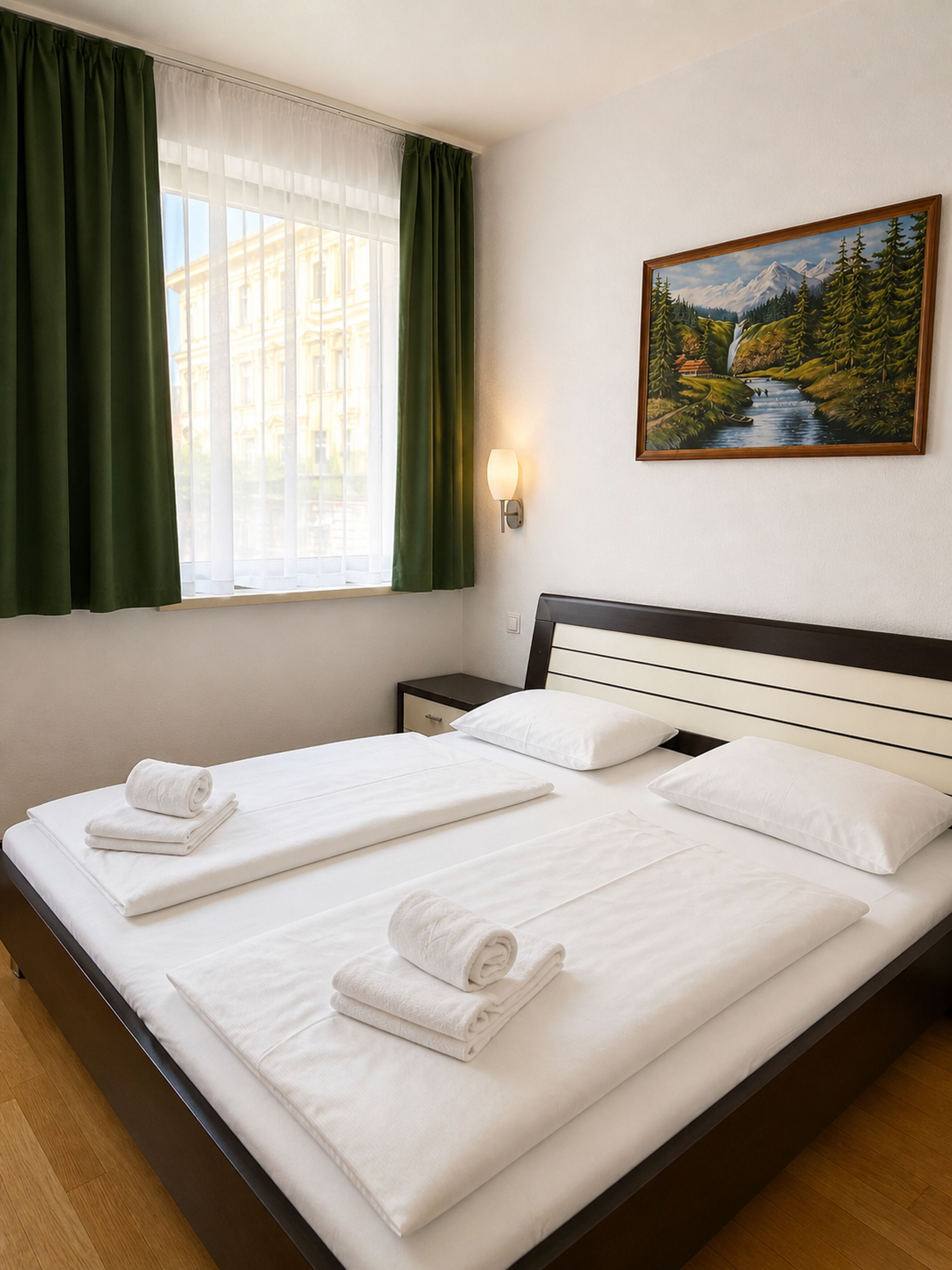 A hotel room with two beds, a painting of a landscape, a nightstand, and a window with curtains.
