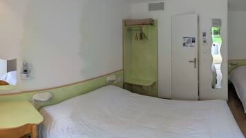 A hotel room with a bed, a desk, a mirror, a wardrobe, and a bathroom.
