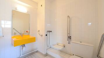 A bathroom with a yellow sink, a mirror, a shower, and a toilet.