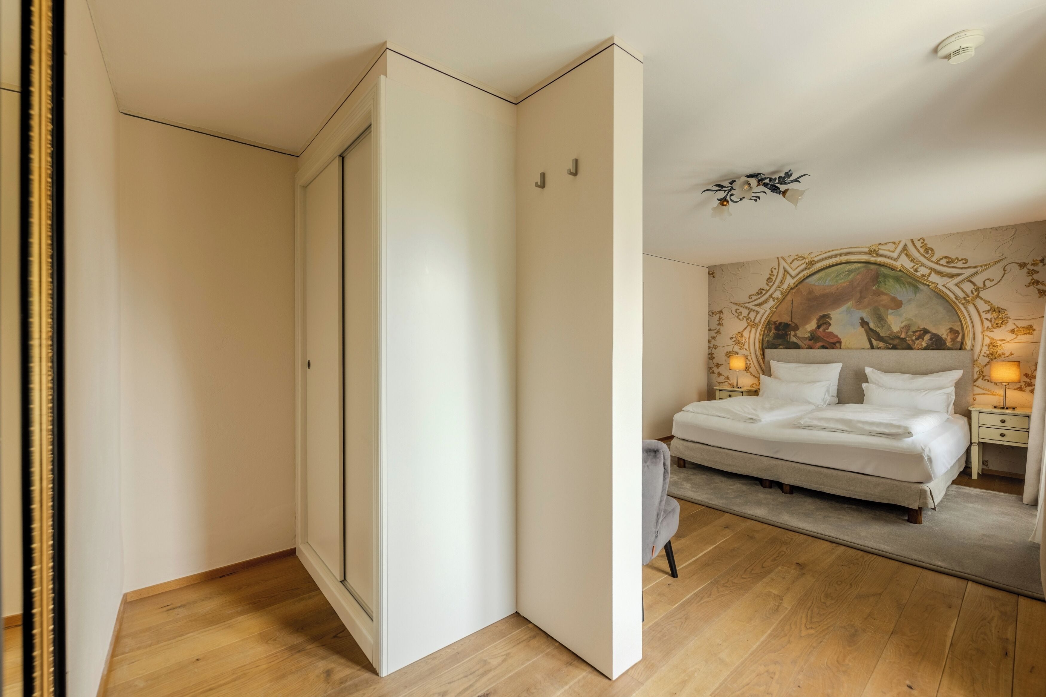 A bedroom with a bed, a nightstand, a lamp, and a painting on the wall.