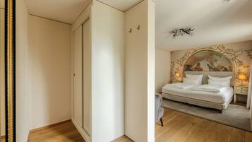 A bedroom with a bed, a nightstand, a lamp, and a painting on the wall.