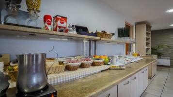 A kitchen with a coffee maker, shelves with food items, and a checkered tablecloth.