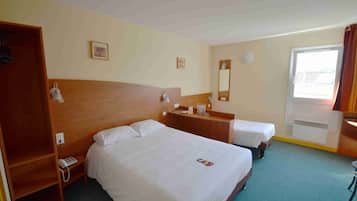 A hotel room with two beds, a wooden wardrobe, a desk, and a window with curtains.