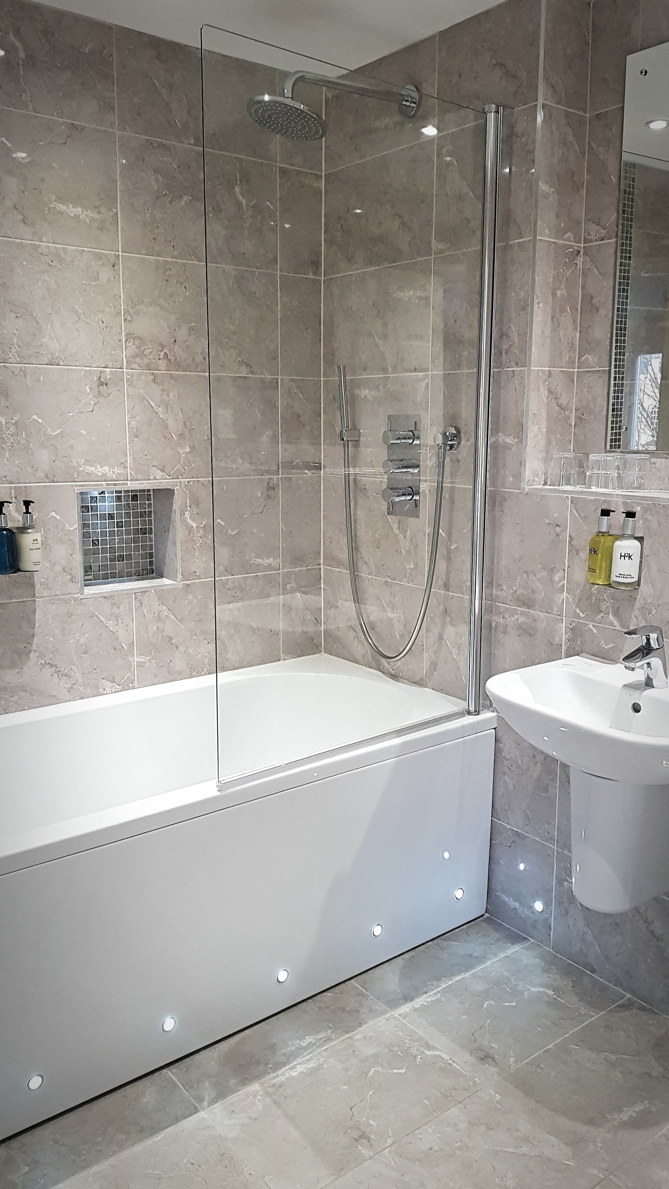 A modern bathroom with a glass-enclosed shower, a freestanding bathtub, and a sink.