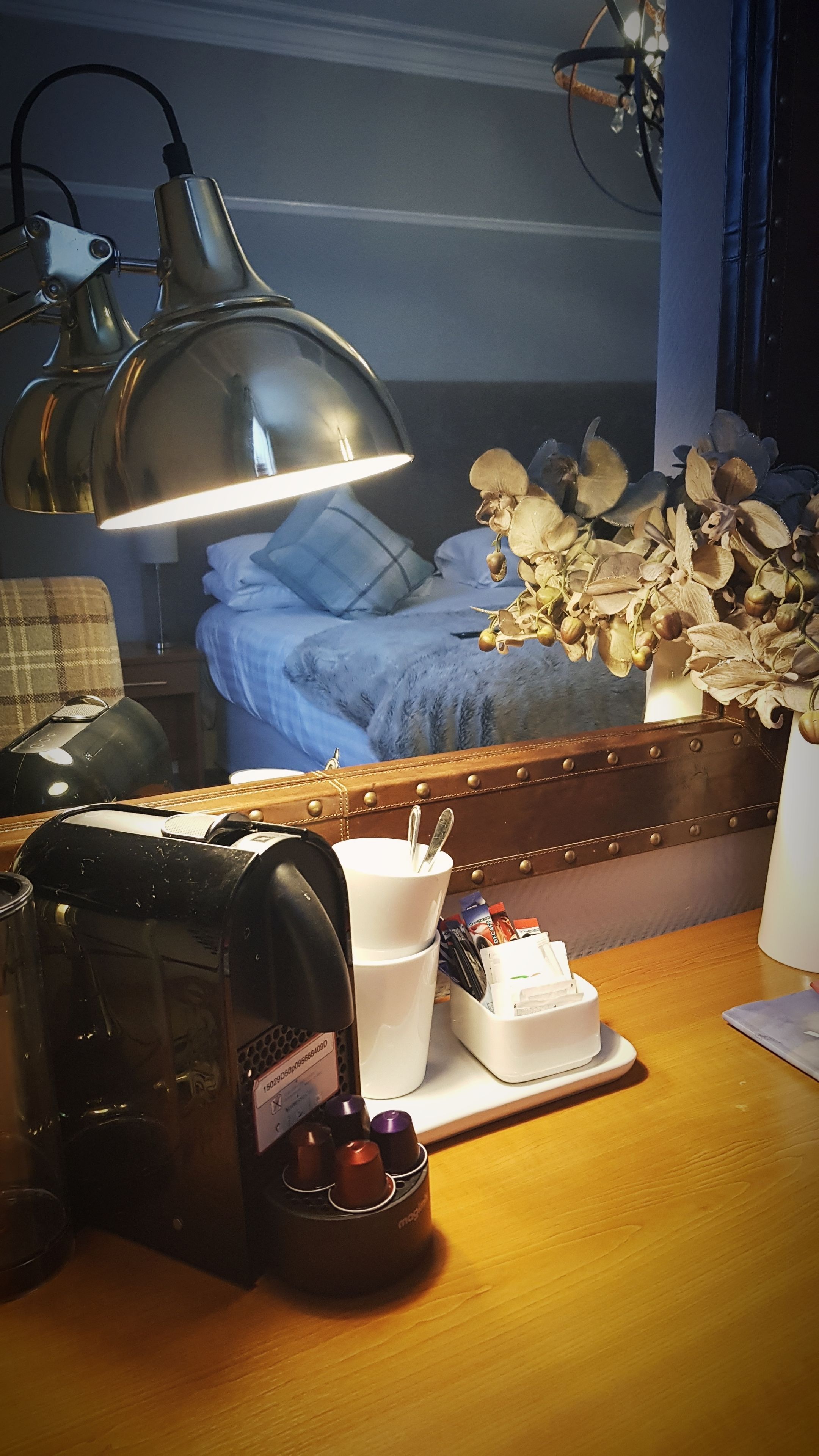 A neatly organized workspace with a desk lamp, a coffee machine, and a tray with cups and a plate of food.