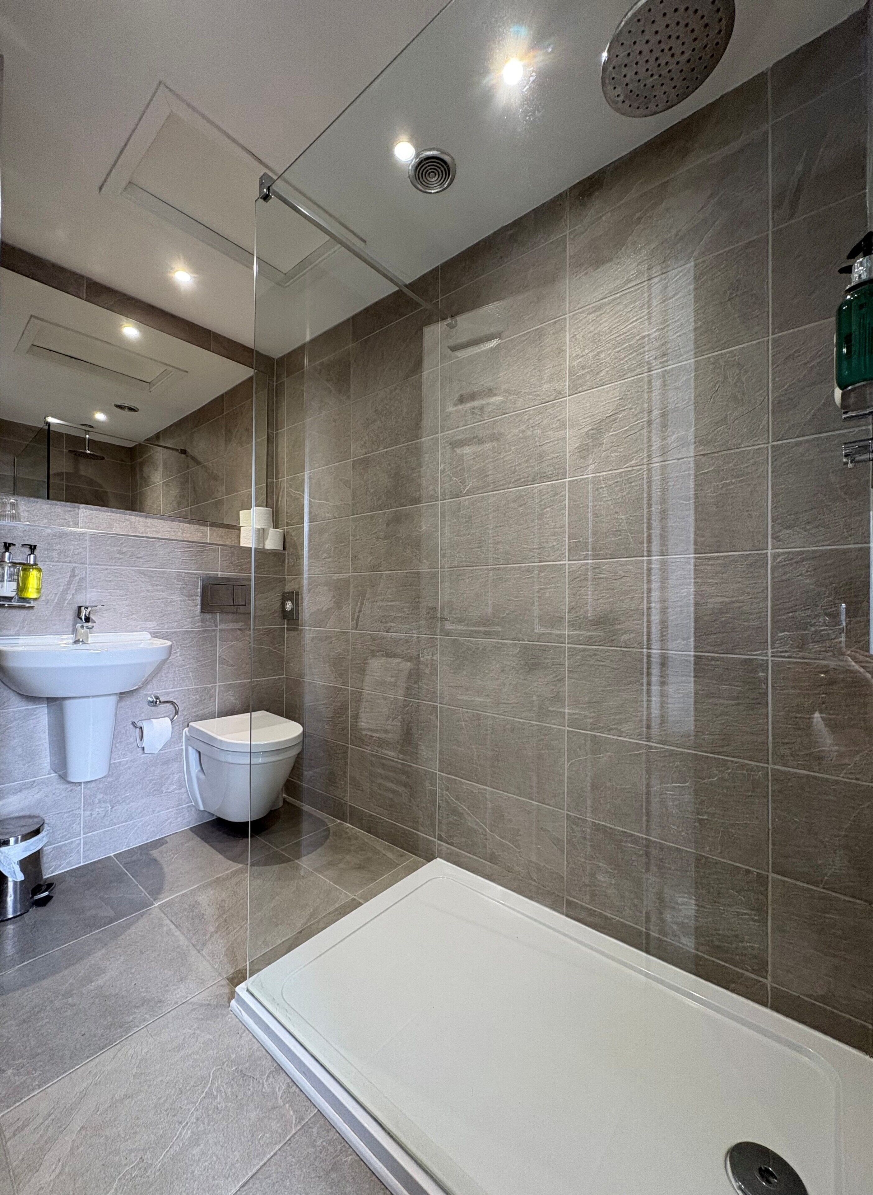 A modern bathroom with a shower, toilet, and sink.