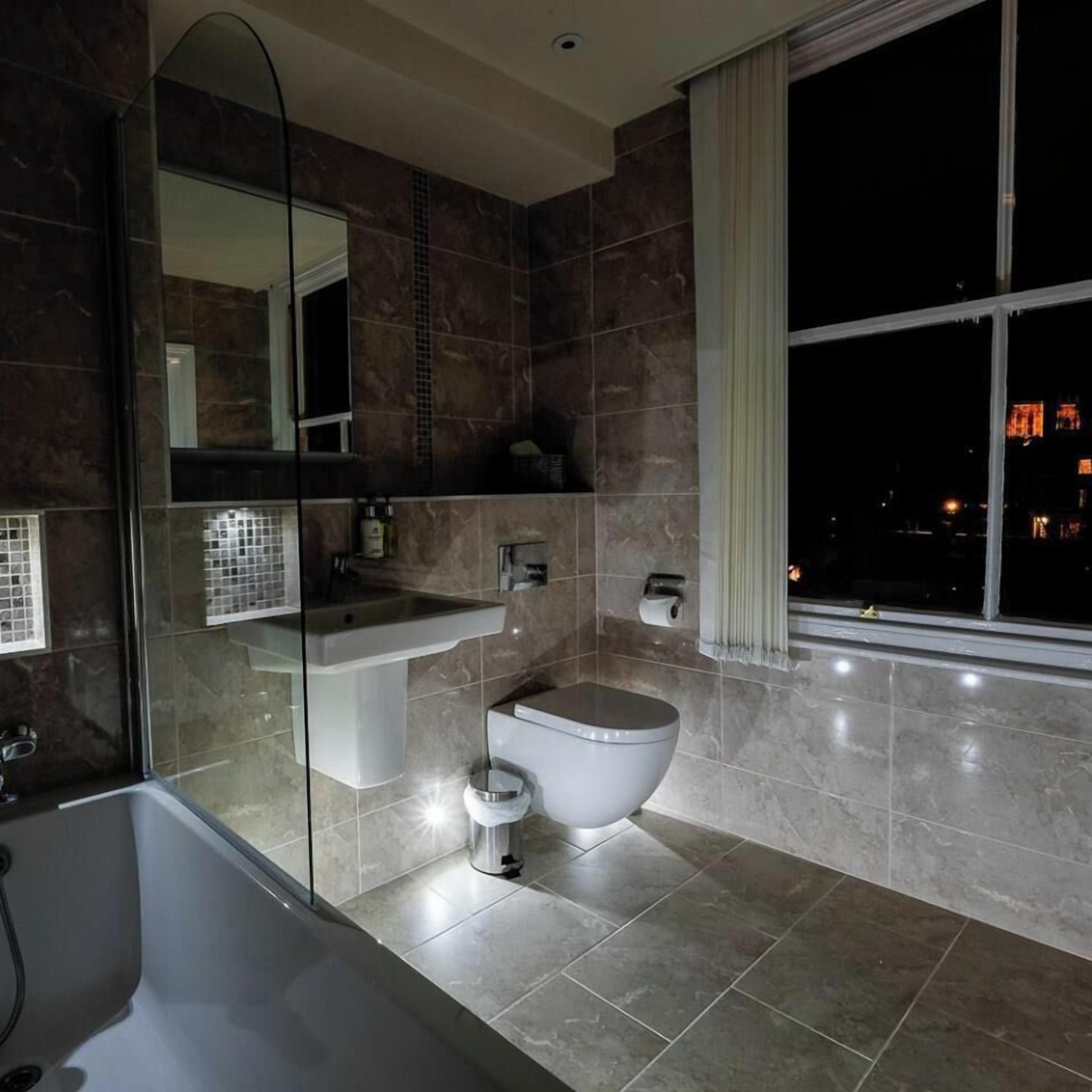 A modern bathroom with a glass-enclosed shower, a white toilet, and a vanity with a mirror.