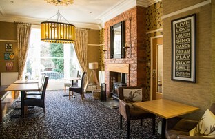A cozy room with a fireplace, a dining area with chairs and a table, and a wall with motivational quotes.