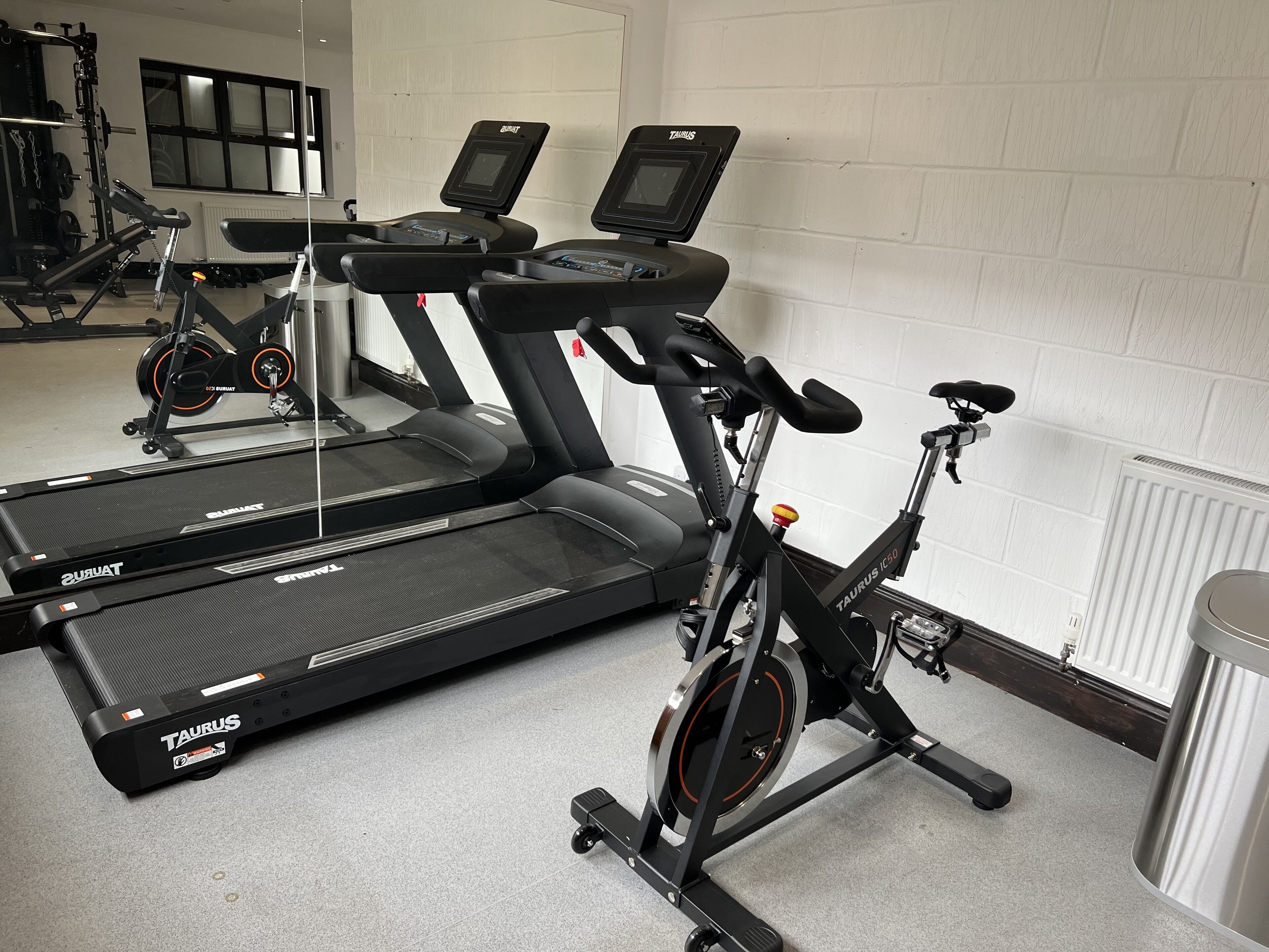 Une salle de sport équipée de nombreux appareils d’exercice, notamment des tapis de course et un vélo d’appartement.