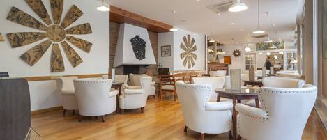 A spacious lobby with white leather armchairs, a wooden floor, and large decorative wall art.