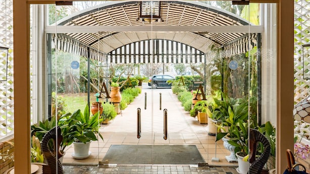 A hotel entrance with a glass door, a covered walkway, and potted plants. - Hotel Araxa - Adults Only (Palma de Mallorca)