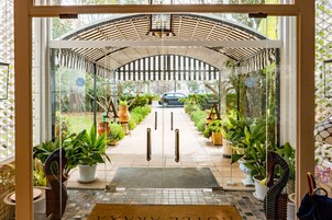 L’entrée d’un hôtel avec une porte en verre, une allée couverte et des plantes en pot.