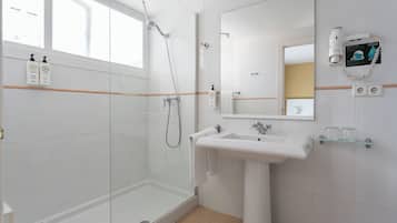 Ein modernes Badezimmer mit Duschkabine aus Glas, einem Standwaschbecken und einem großen Spiegel.