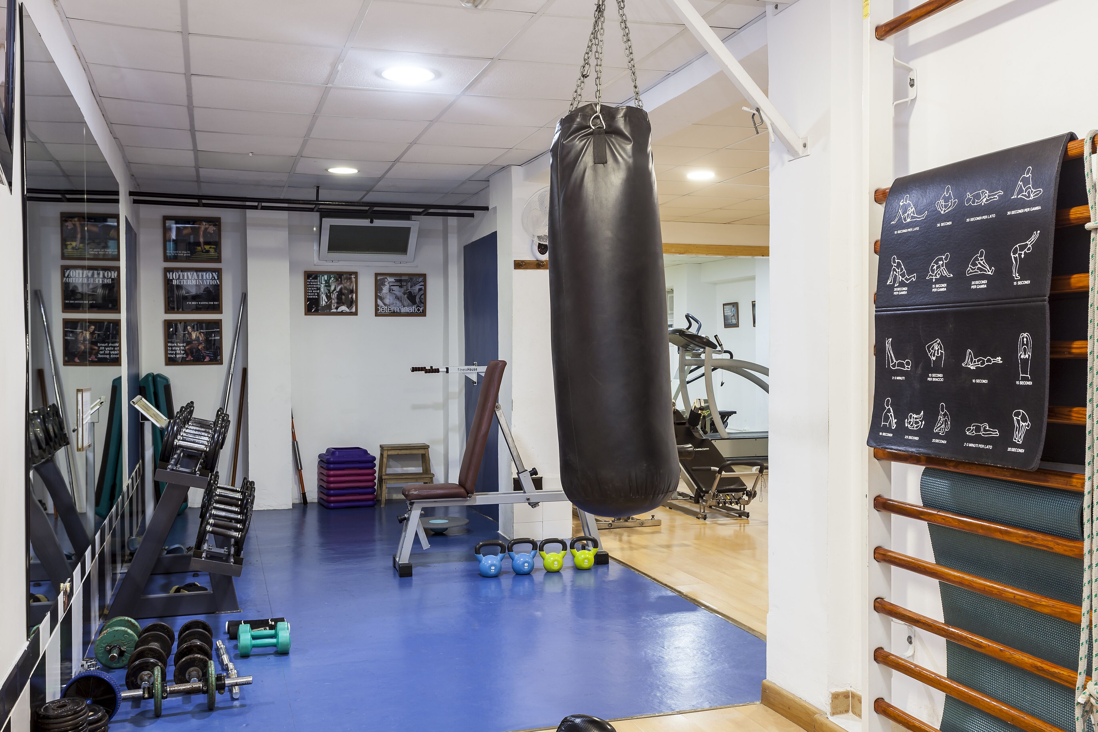 Ein Fitnessraum mit Krafttrainingsgeräten, Kettlebells und einem Schlagbeutel.