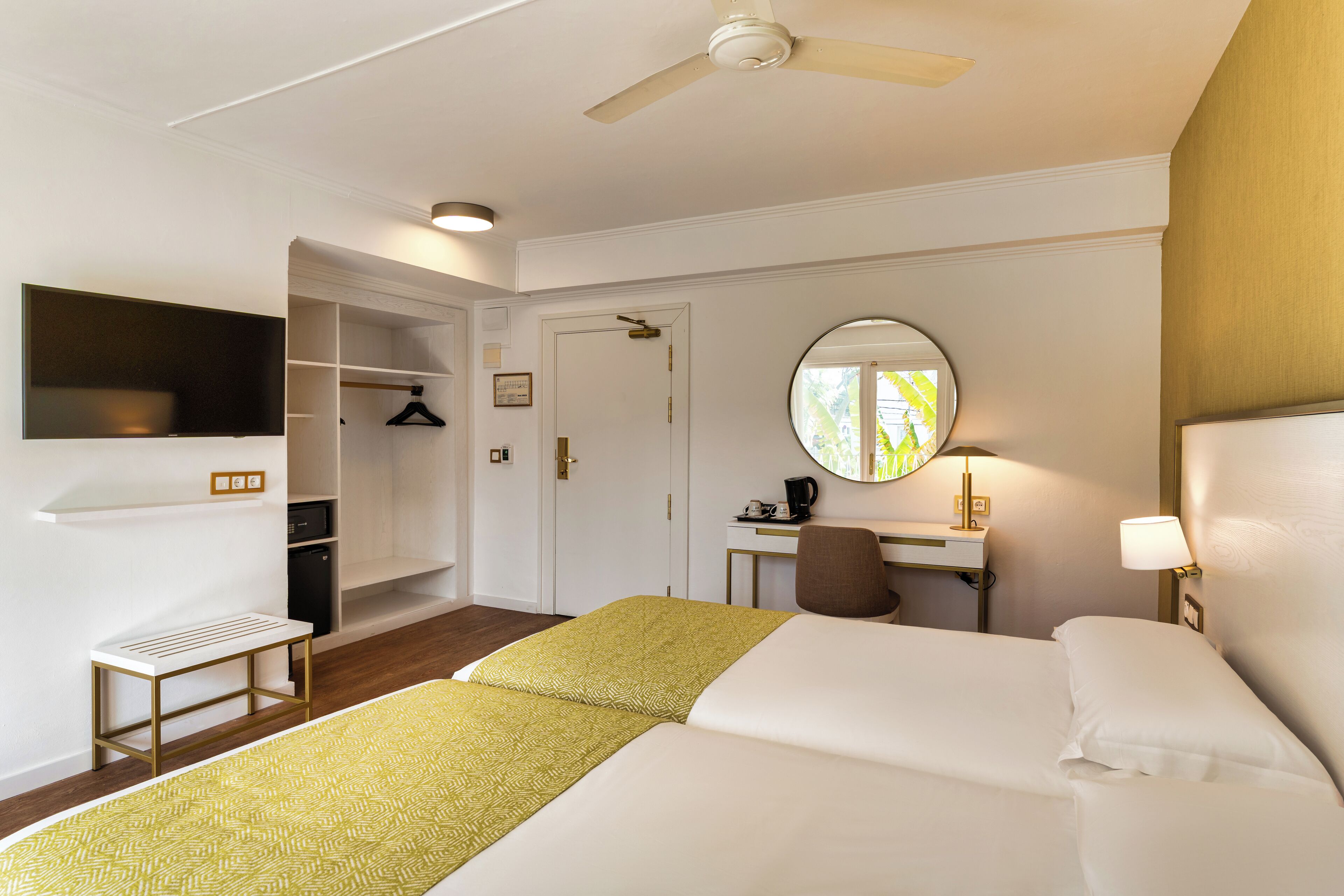 A hotel room with a bed, a desk, a chair, a TV, and a wardrobe.