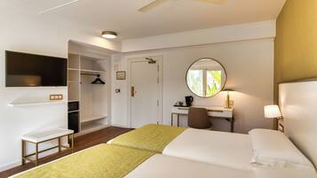 A hotel room with a bed, a desk, a chair, a TV, and a wardrobe.