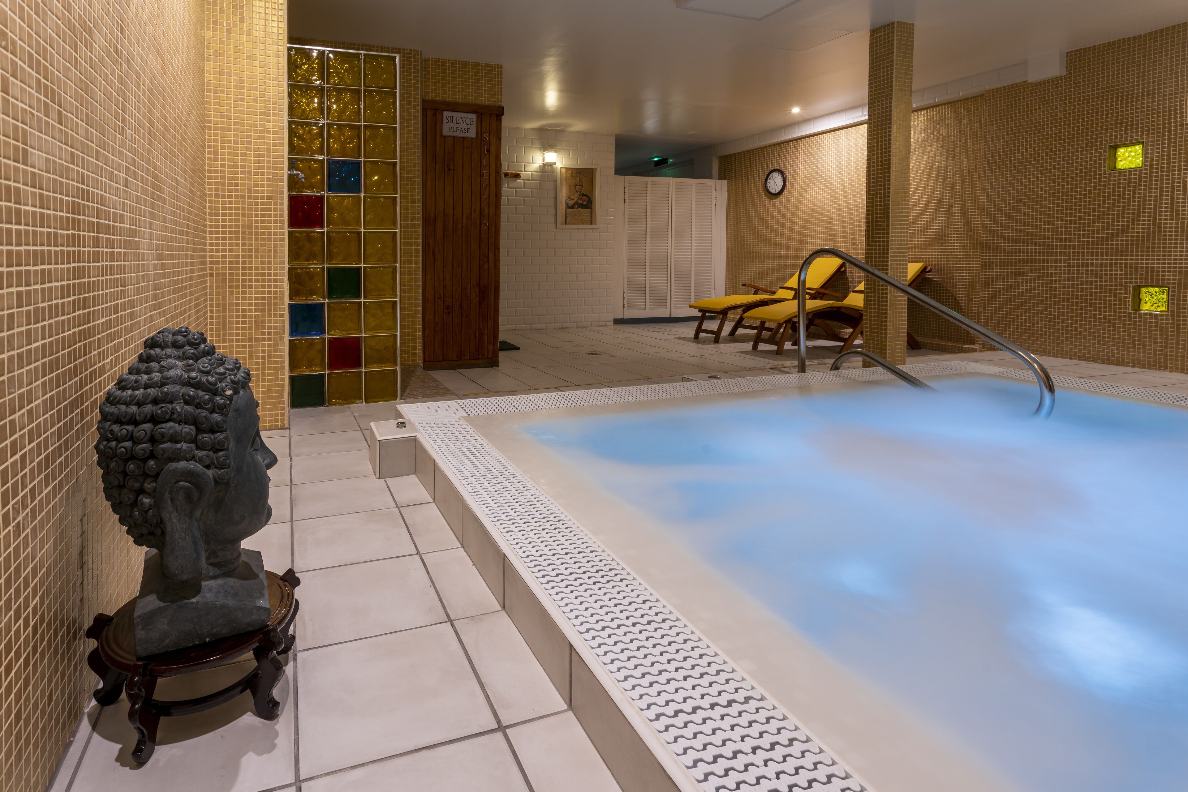 Zona de spa con hidromasaje, asientos y una estatua.